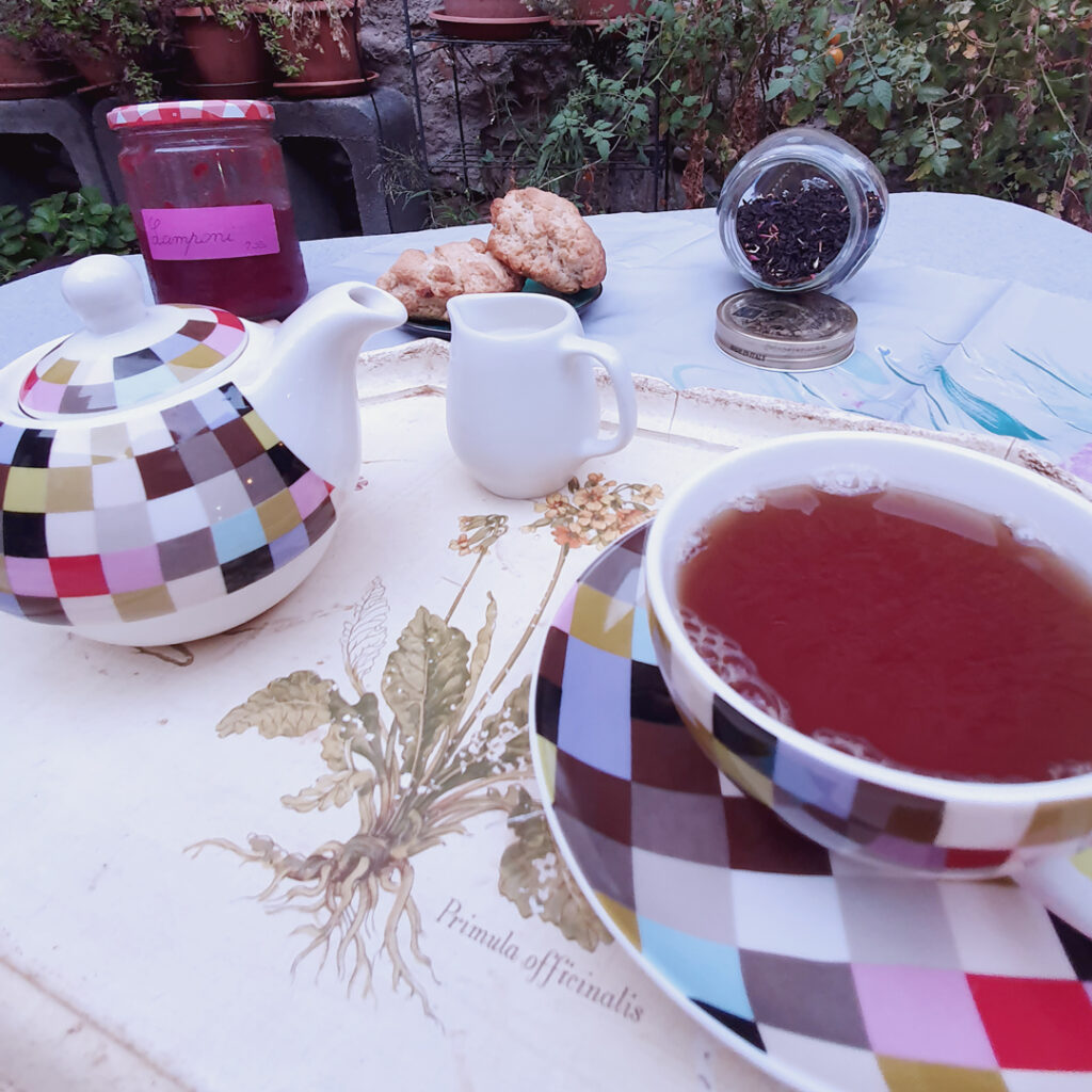 Tè nero servito su un vassoio con lattiera, scones e confettura di lamponi fatta in casa.